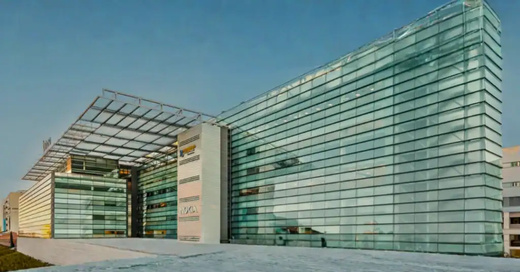 Edificio corporativo moderno de cristal con el logotipo de Ubimia, símbolo de la nueva etapa de Ubimia Compliance y su consolidación empresarial.